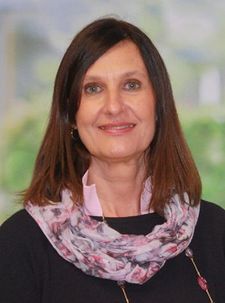 Porträt einer Frau mit schulterlangen braunen Haaren und floralem Schal