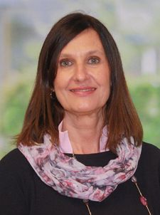 Porträt einer Frau mit schulterlangen braunen Haaren und floralem Schal
