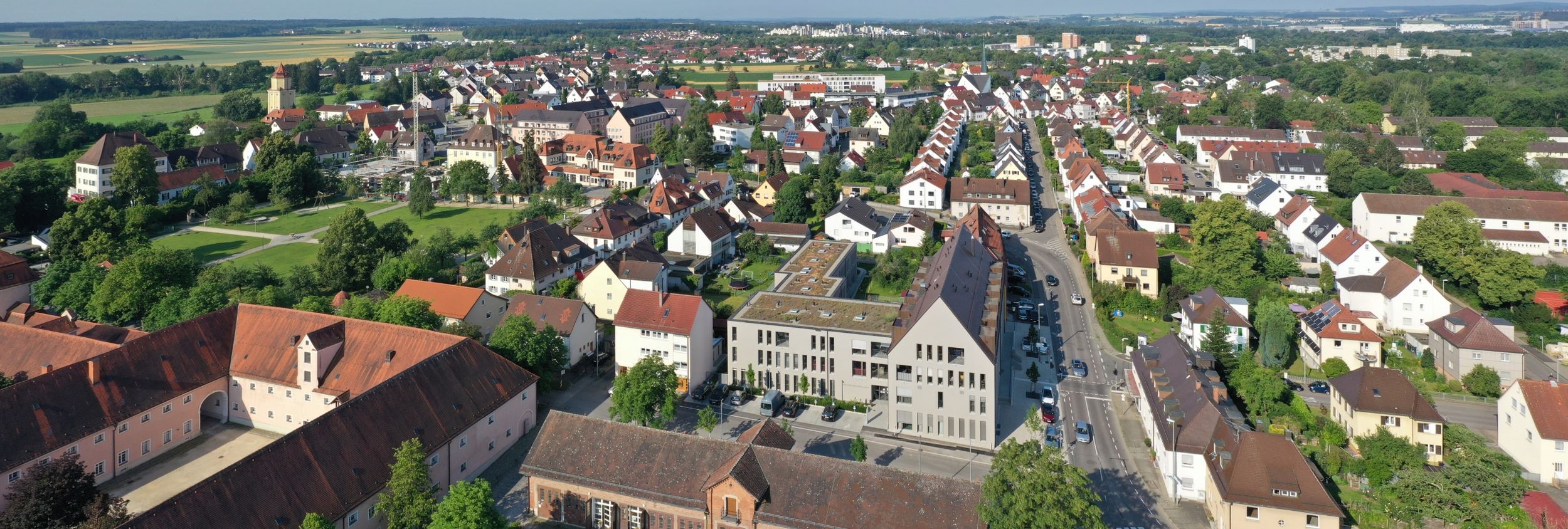 Luftaufnahme einer Kleinstadt mit roten Dächern Kirchturm und Park